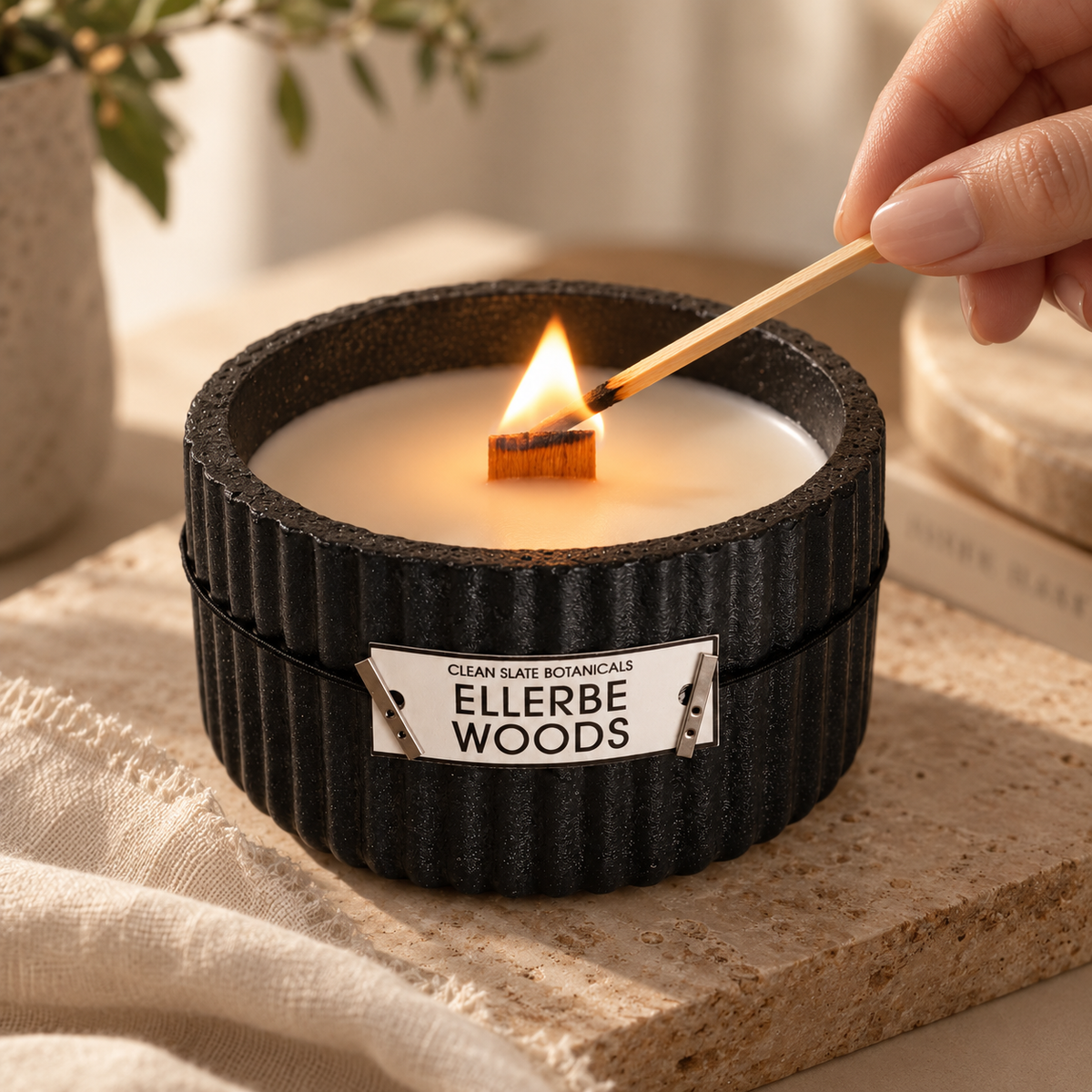 Ellerbe Woods Candle in a black artisanal concrete vessel with ribbed pattern, lit by a wooden matchstick