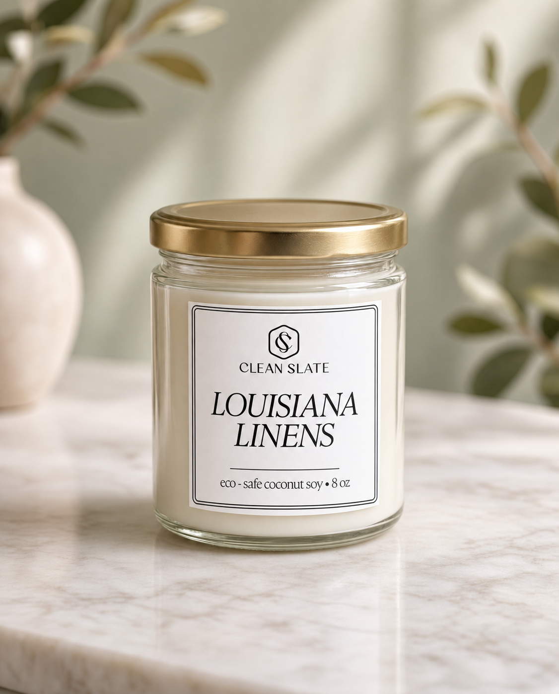 Glass jar fresh linen candle with white wax and gold lid labeled Louisiana Linens clean slate 8 oz