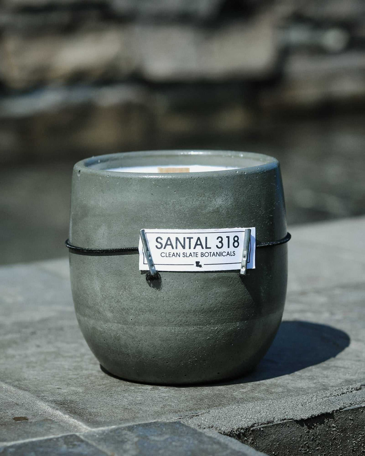 Santal 318 candle in a dark gray concrete vessel with a smooth finish and a white labeled band