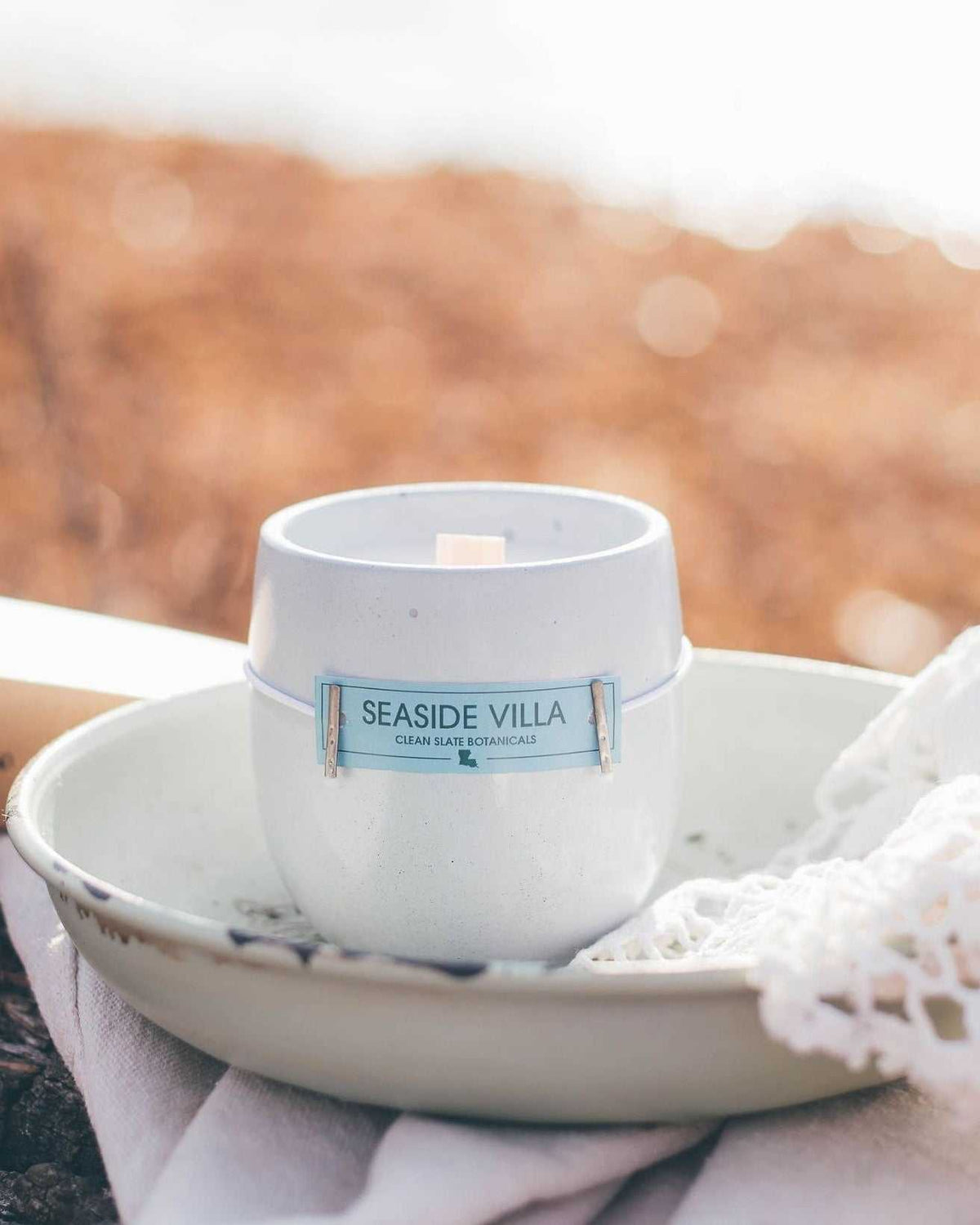Seaside Villa Candle in a white concrete vessel with a pale blue label, clean coastal design and centered wick