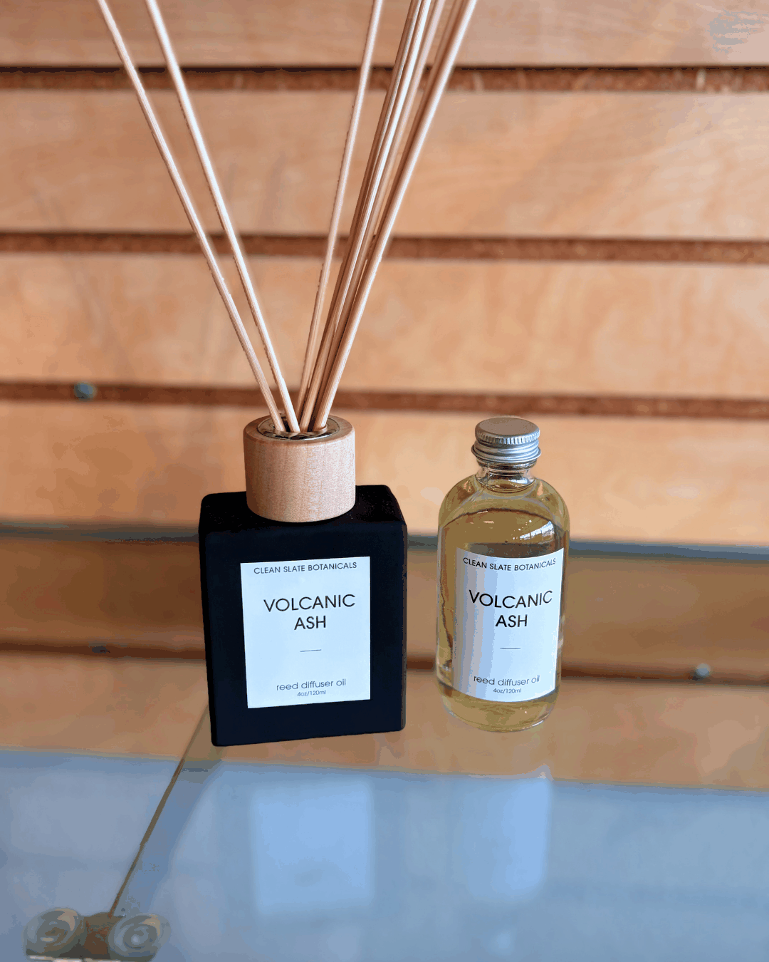 Volcanic Ash Reed Diffuser set with a black square bottle, wooden reeds, and a small clear refill bottle