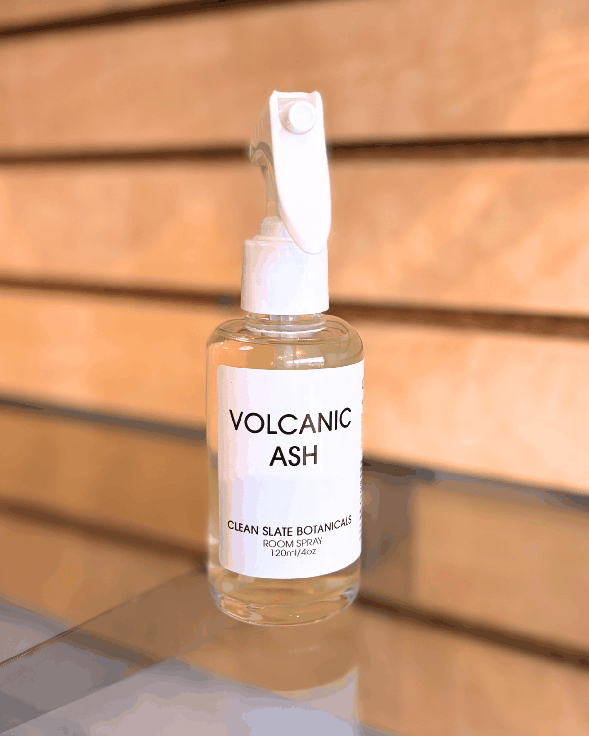 Volcanic Ash room spray in a clear bottle with golden liquid, white trigger sprayer and minimalist label
