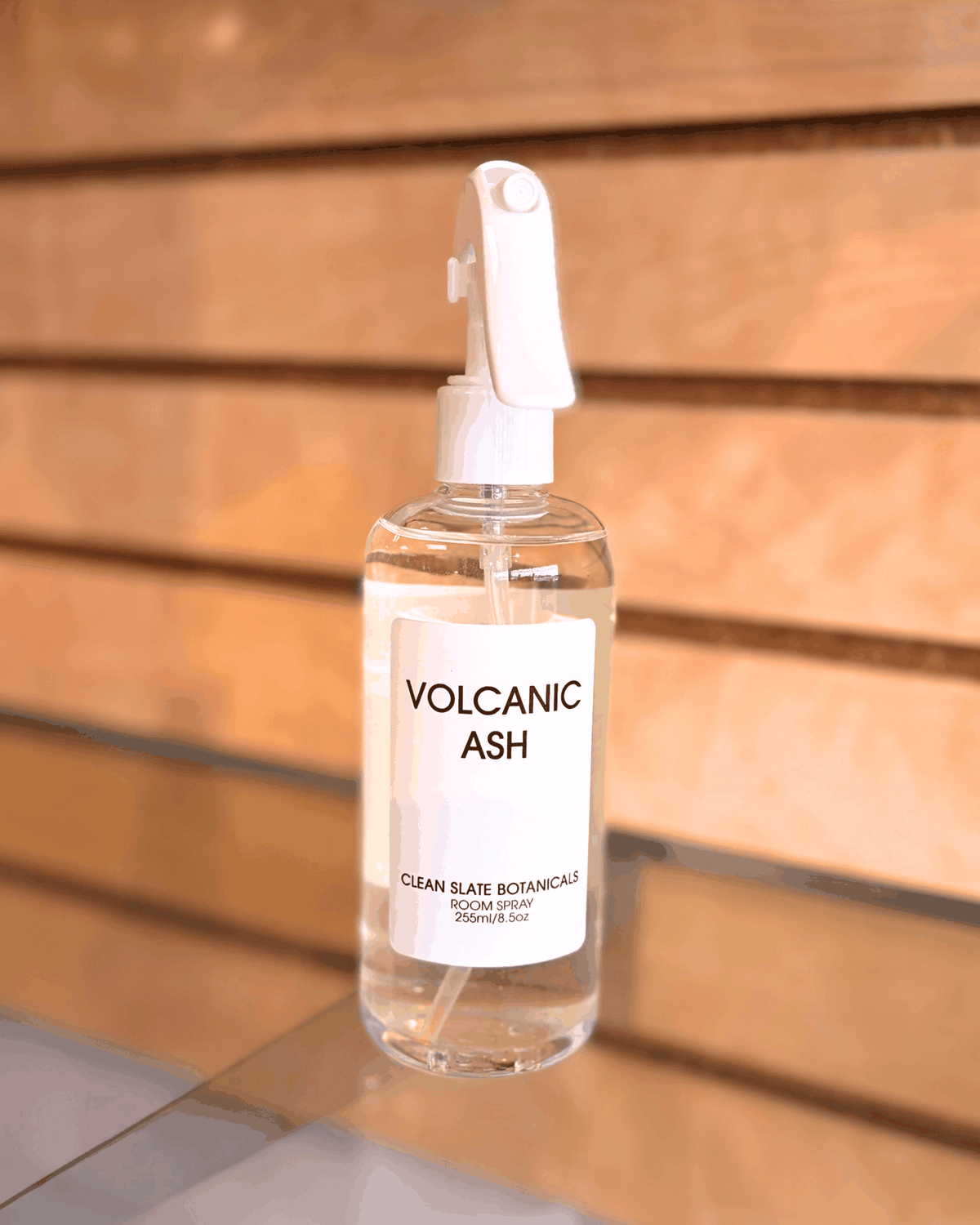 Volcanic Ash room spray in a clear bottle with a white trigger sprayer and a minimal white label